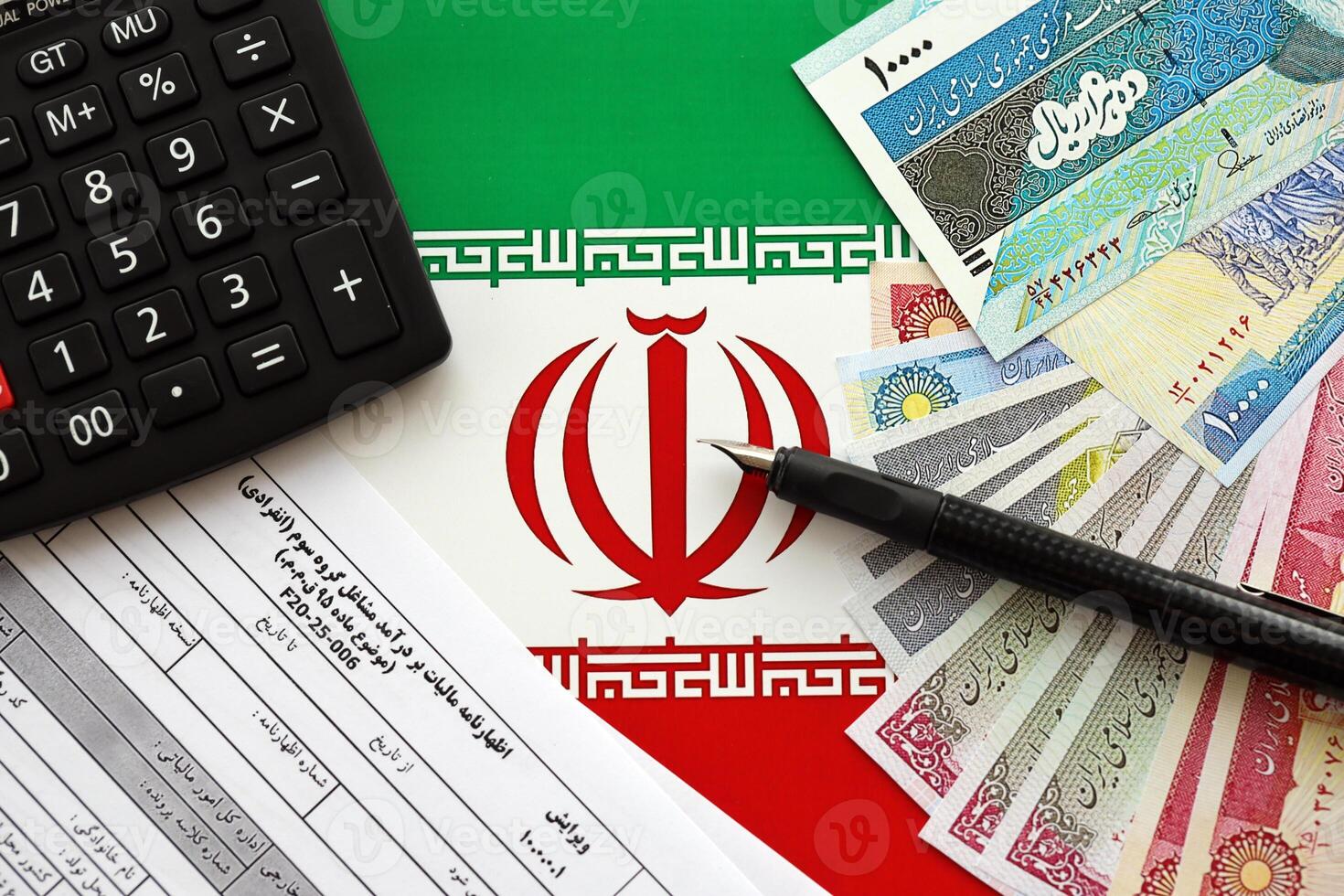 Iranian annual income tax return form F20-25-006 ready to fill on table with pen, calculator and iranian money on flag photo