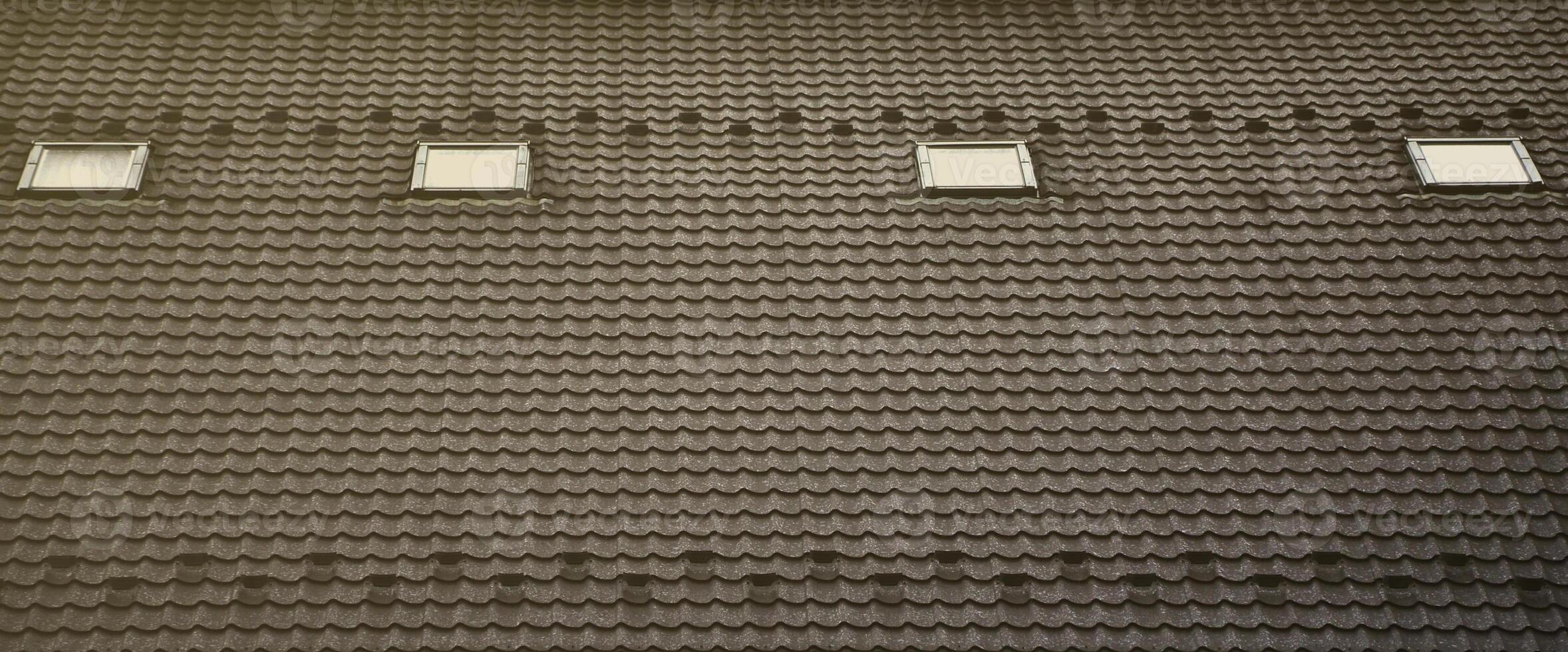The texture of the roof with a roof made of metal, covered with drops from the rain. Several pane windows are built into the roof photo