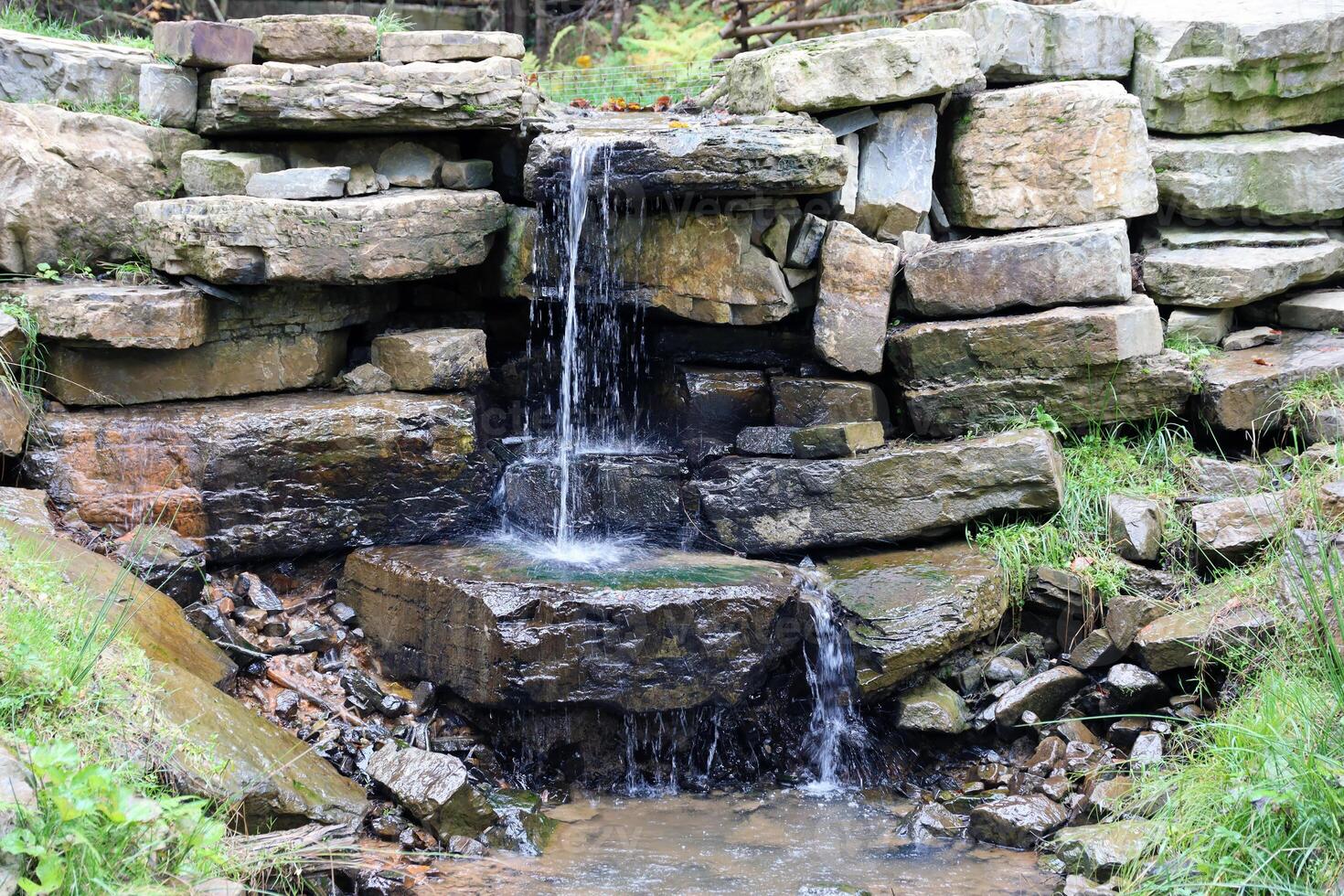 Close up of a small waterfall spilling over moss covered rocks in regional park. Handmade river waterfall photo