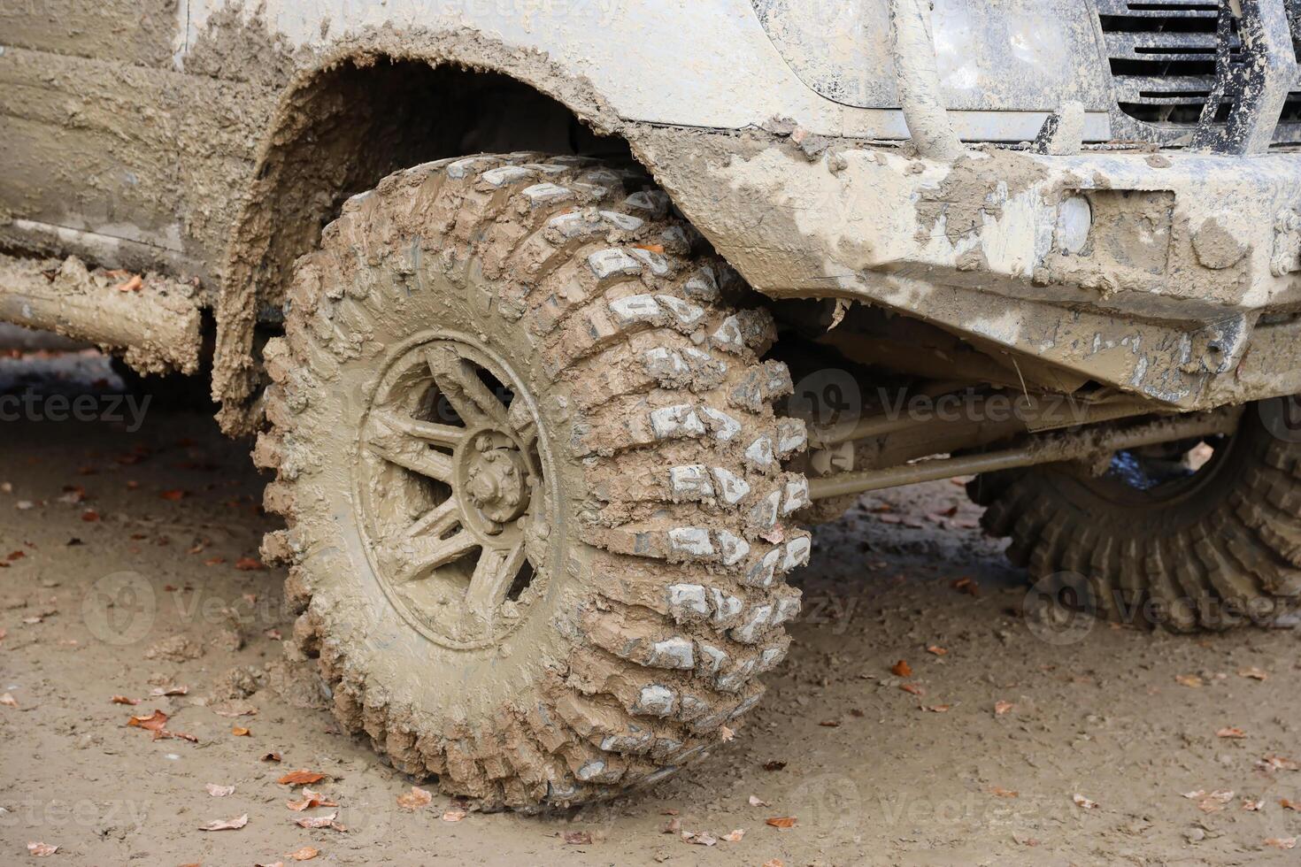Wheel closeup in a countryside landscape with a mud road. Off-road 4x4 suv automobile with ditry body after drive in muddy road photo