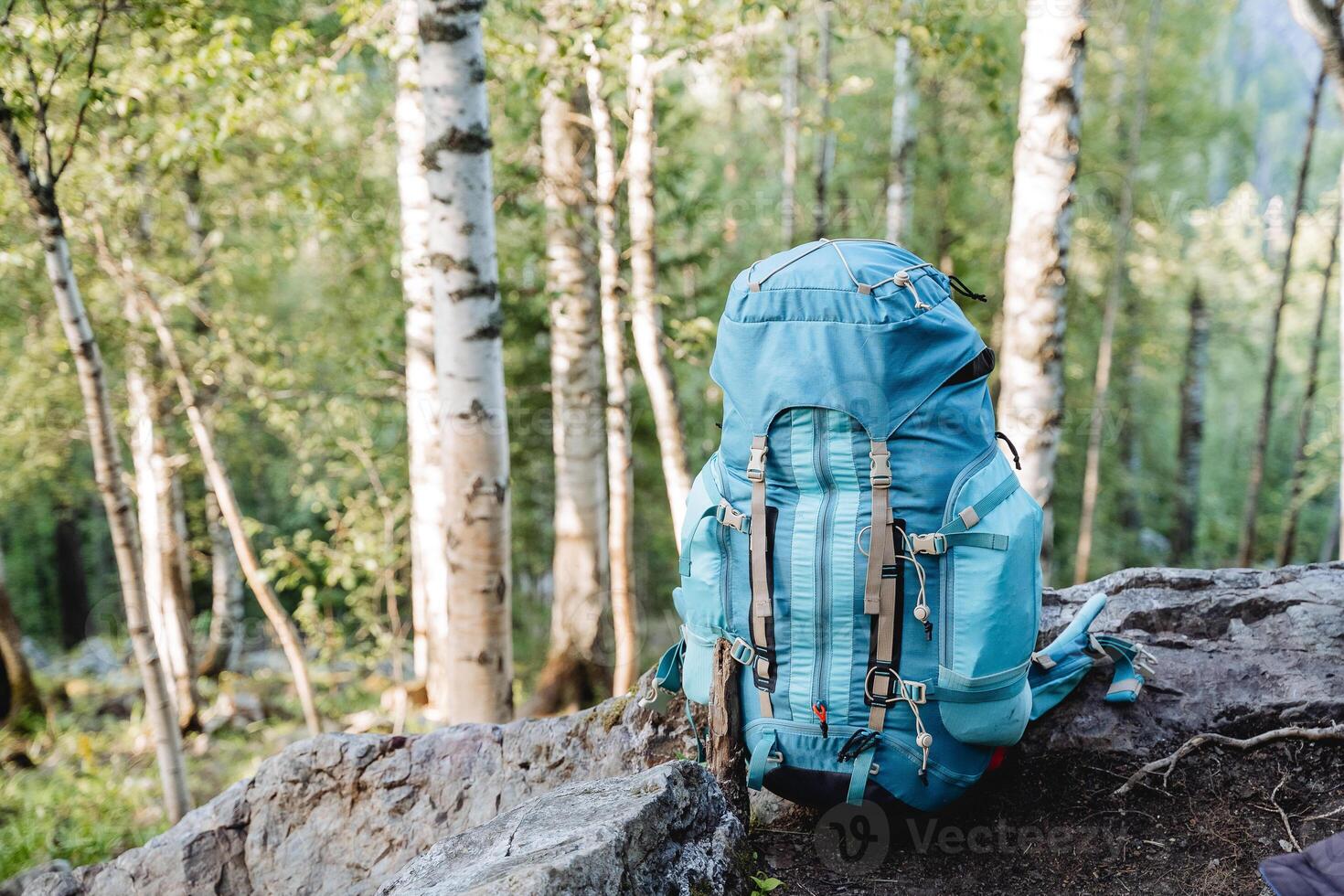 A tourist backpack stands on the ground, a blue bag for things, sports equipment, a hike in the mountains, a bowl for transportation. photo