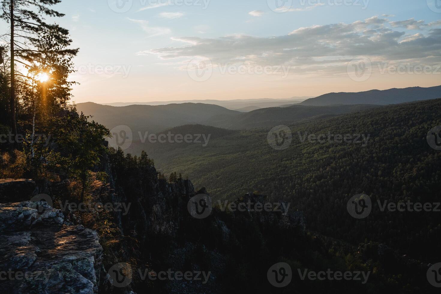 View of the rock ridge in the dark, evening lighting, the sun rolls towards sunset, glare of rays through the trees, mountain landscape, nature of Russia photo