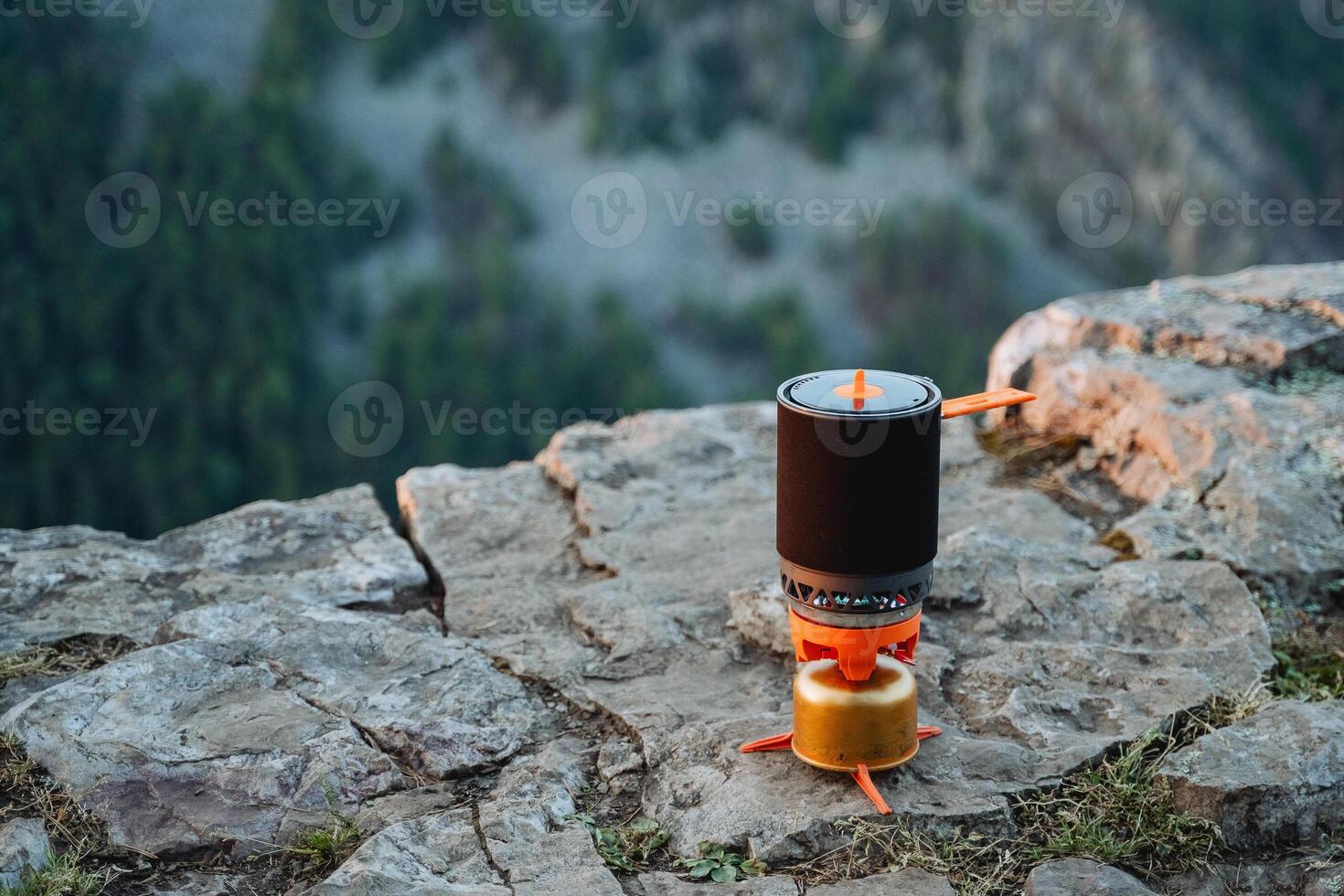 Tourist utensils bowler standing on the edge of a rock rock, camping gas for cooking on a hike, compact equipment for mountaineering. photo