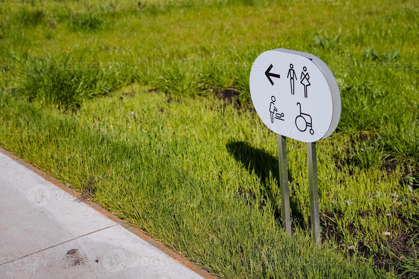 Sign sign toilet stands on the lawn, designation of the direction of the room for mother and child, public toilet arrow, banner alert. photo