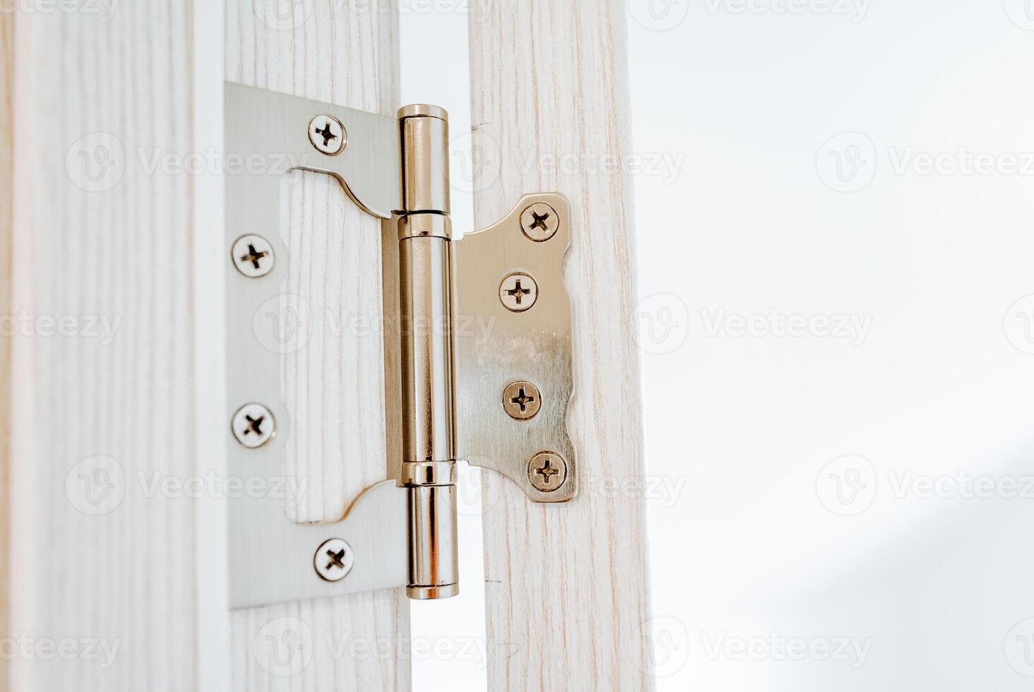 The hinge of the door is shot close-up, steel hinges are attached to the jamb of the doorway, cross-shaped screws are screwed into the door, interior details. photo