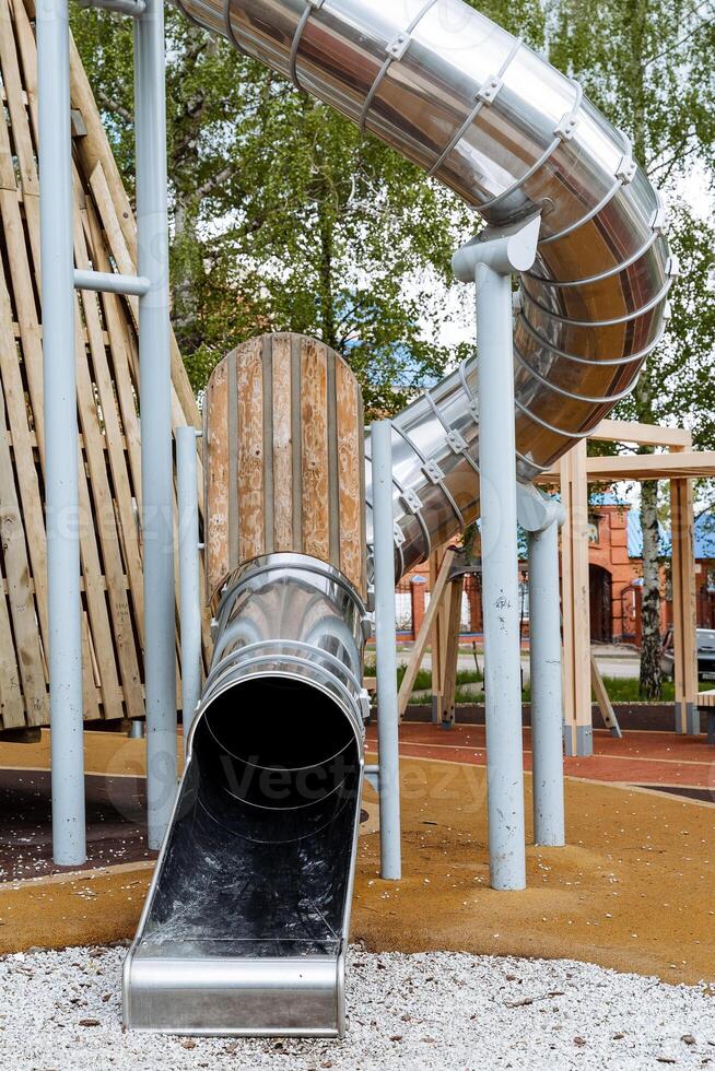 Screw slide made of metal, stainless steel on the playground, ride down the slide in the pipe, round pipe is lowered from the top for skating. children's attraction. photo