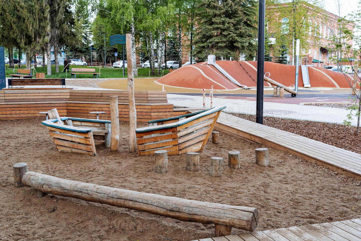 Children's playground in the fresh air, a wooden boat for the games of kids, a large sandbox in the courtyard of the house, a log for walking with your feet. photo