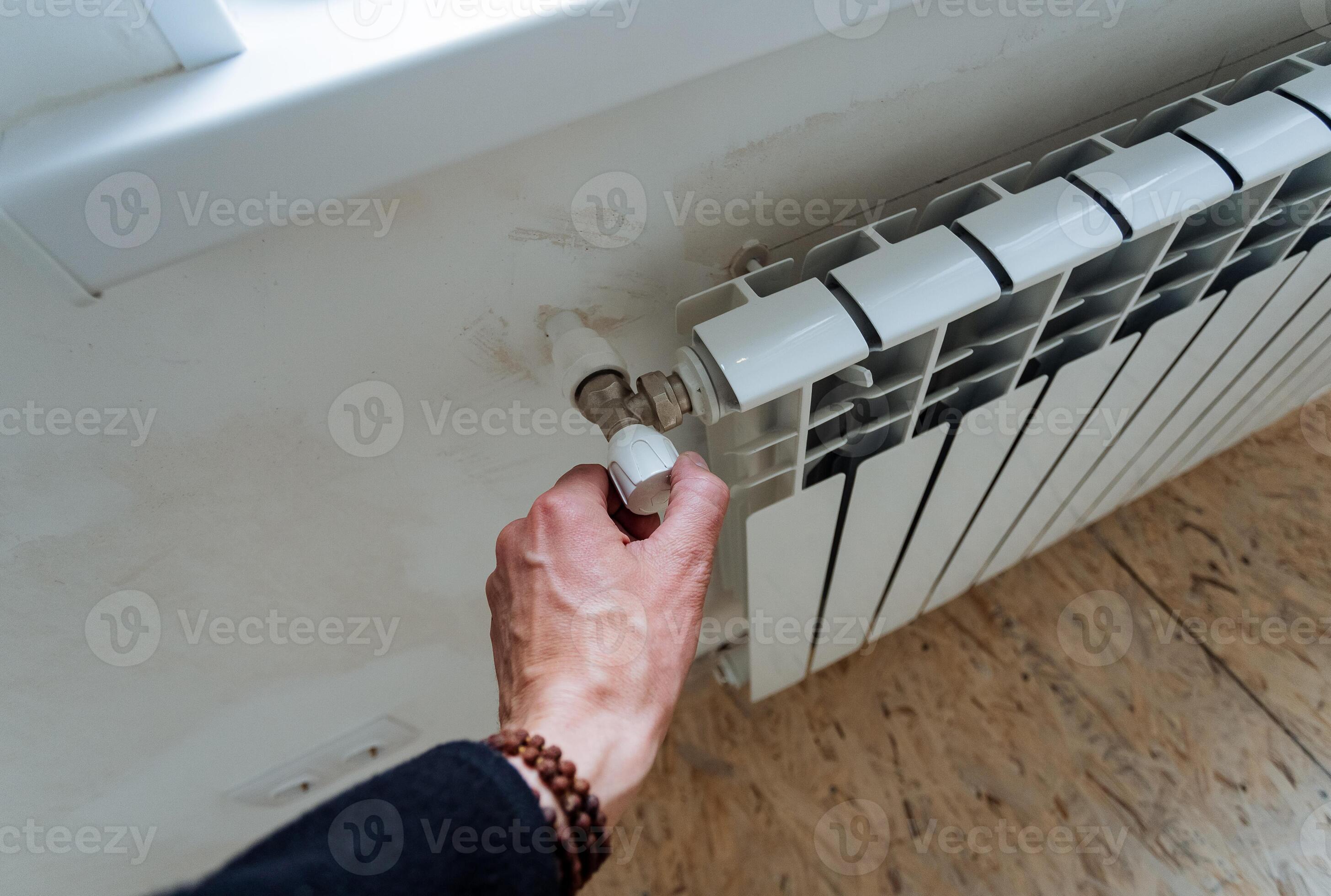 The hand adjusts the temperature level in the radiator, the faucet