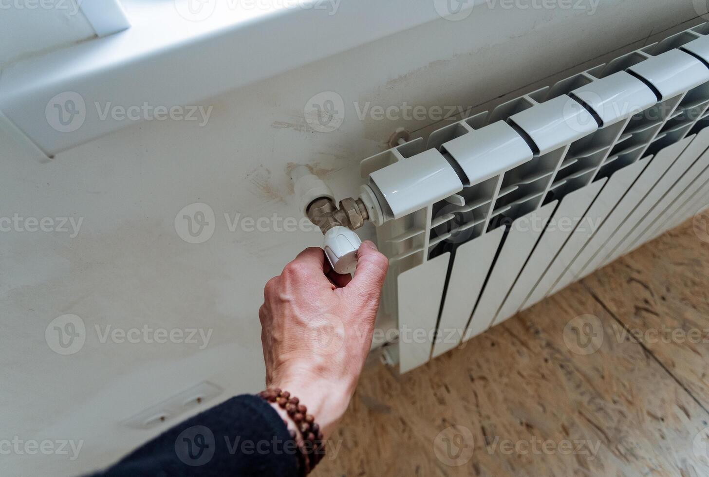 The hand adjusts the temperature level in the radiator, the faucet reduces the heat in the house, smooth adjustment of the power of the water flow into the pipes. home heat exchanger. photo