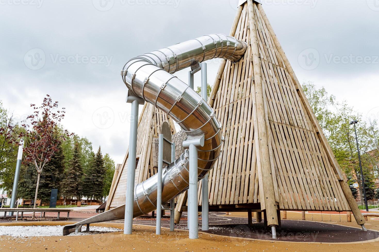 Pyramid slide made of wood, spiral tube slide, metal structure, play with children, playground, outdoor play space. photo