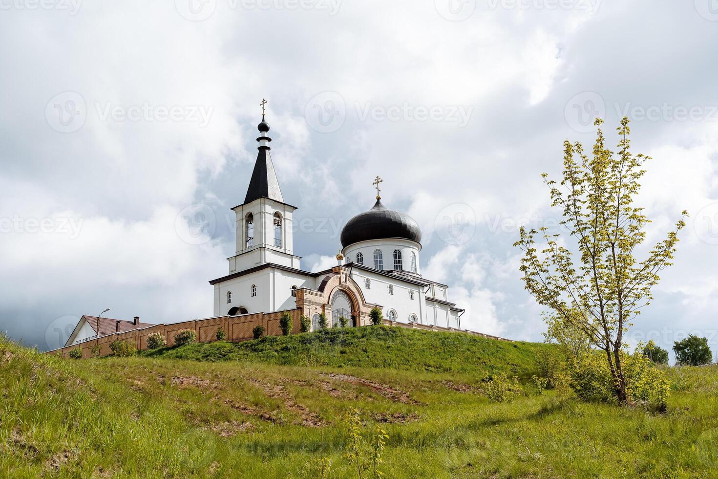 The Church of the Archangel Michael the city of Birsk Russia Bashkortostan, an Orthodox temple, a monastery stands on a mountain, a brick fortress wall, a white church. photo