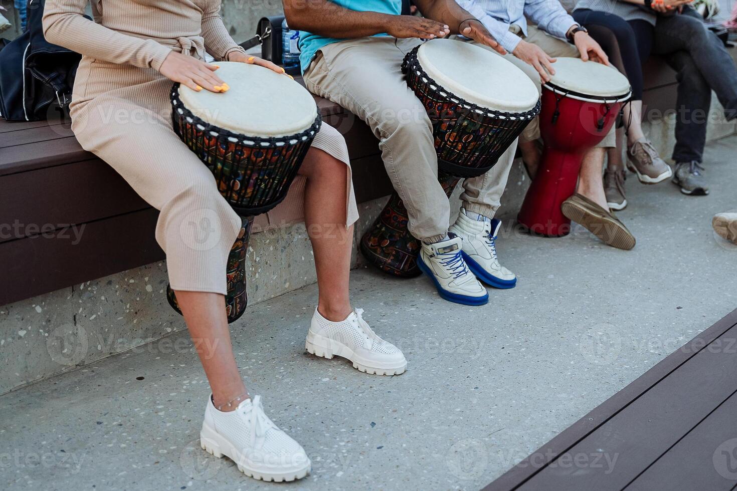 A group of people play drums on the streets of the city, hands beat the rhythm on the djemba, street musicians, a trio of percussion, a performance in the park. photo