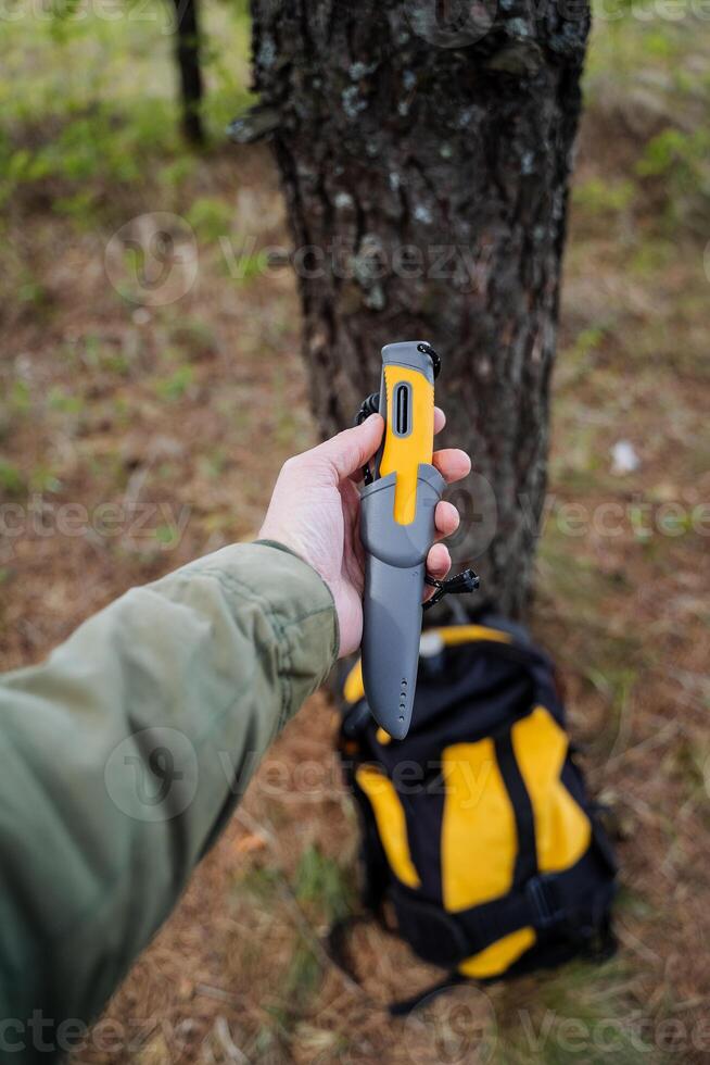 A bushcraft knife lies in a man's hand, a tactical knife with a plastic handle in the sheath, a yellow handle. photo