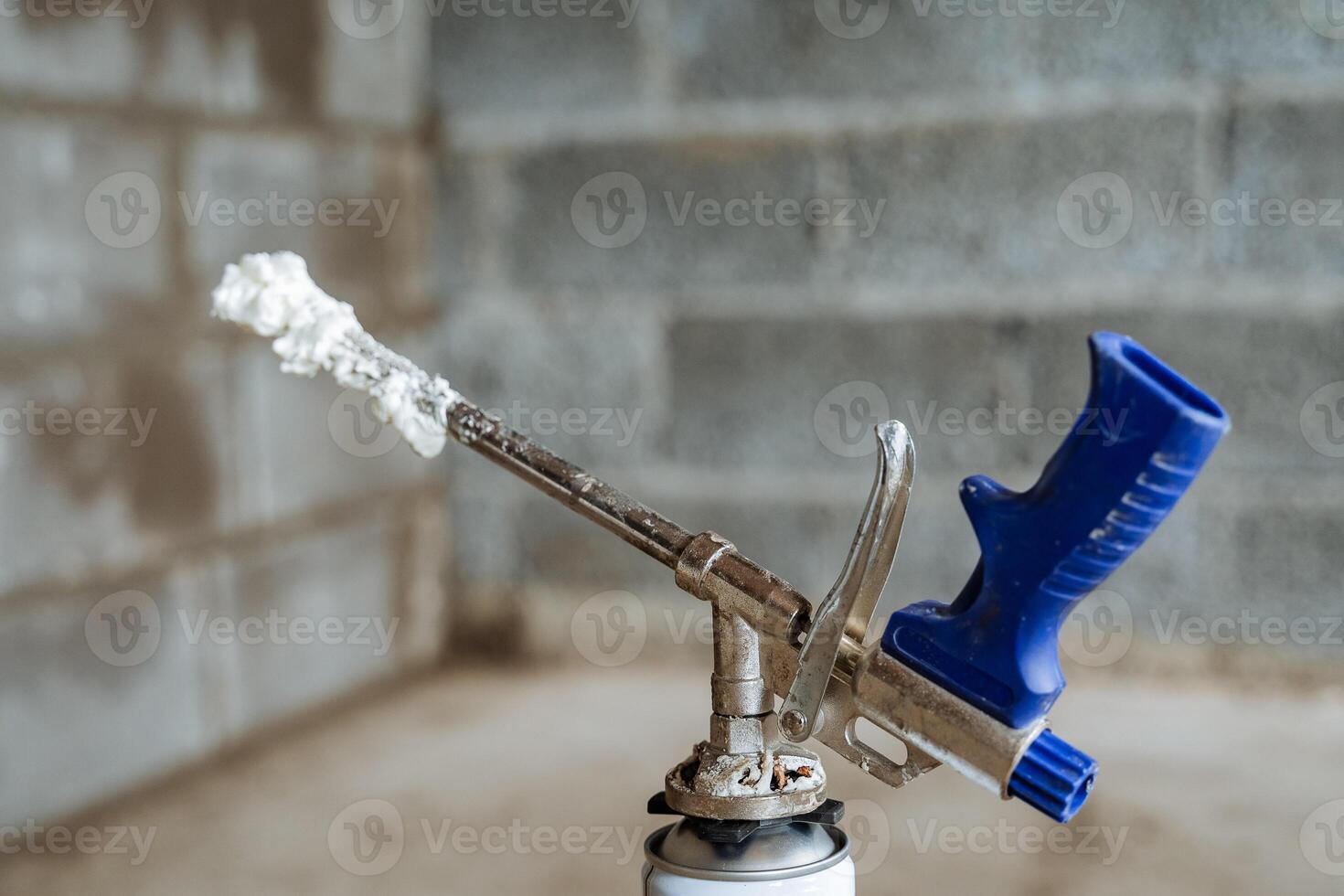 Construction gun for spray foam, foam dried on the tube. blue handle of the iron barrel. photo