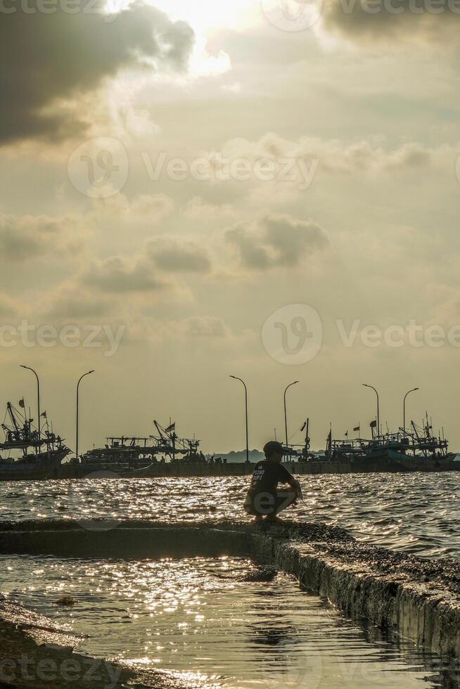 Jepara, Central Java, April 7, 2024 -Fishermen at the Jepara pier with a sunset sky as the background with free space for photocopies. nature concept for advertising. photo
