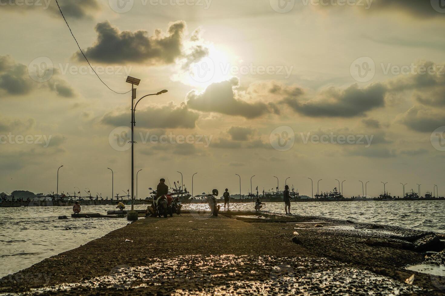 Jepara, Central Java, April 7, 2024 -Fishermen at the Jepara pier with a sunset sky as the background with free space for photocopies. nature concept for advertising. photo