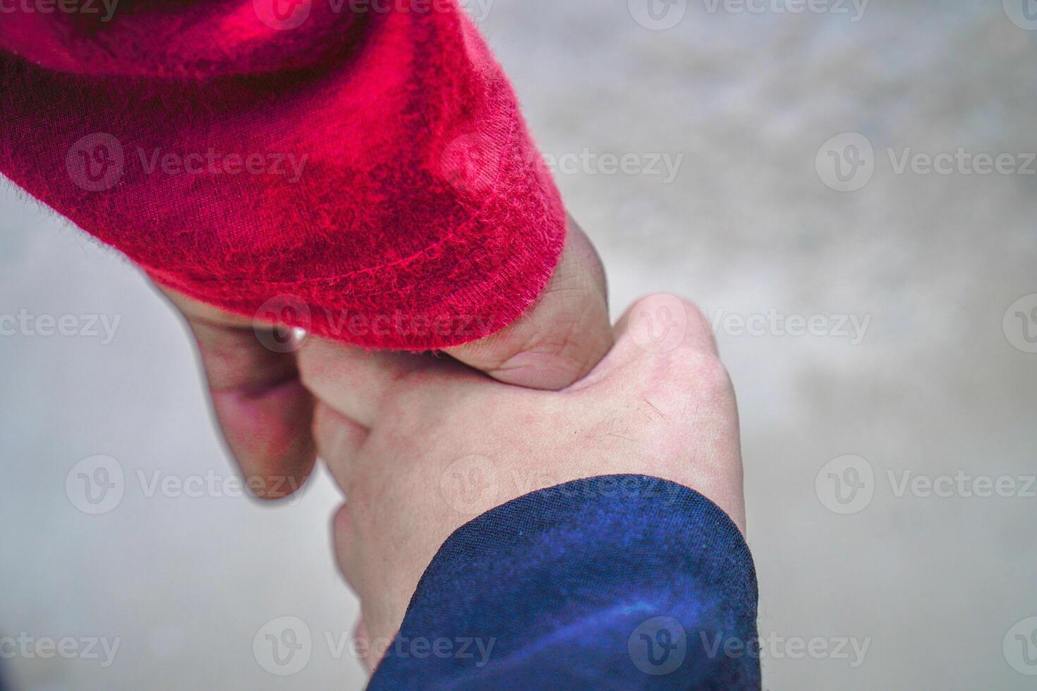 the hands of a couple holding hands against the background of beach sand. photo