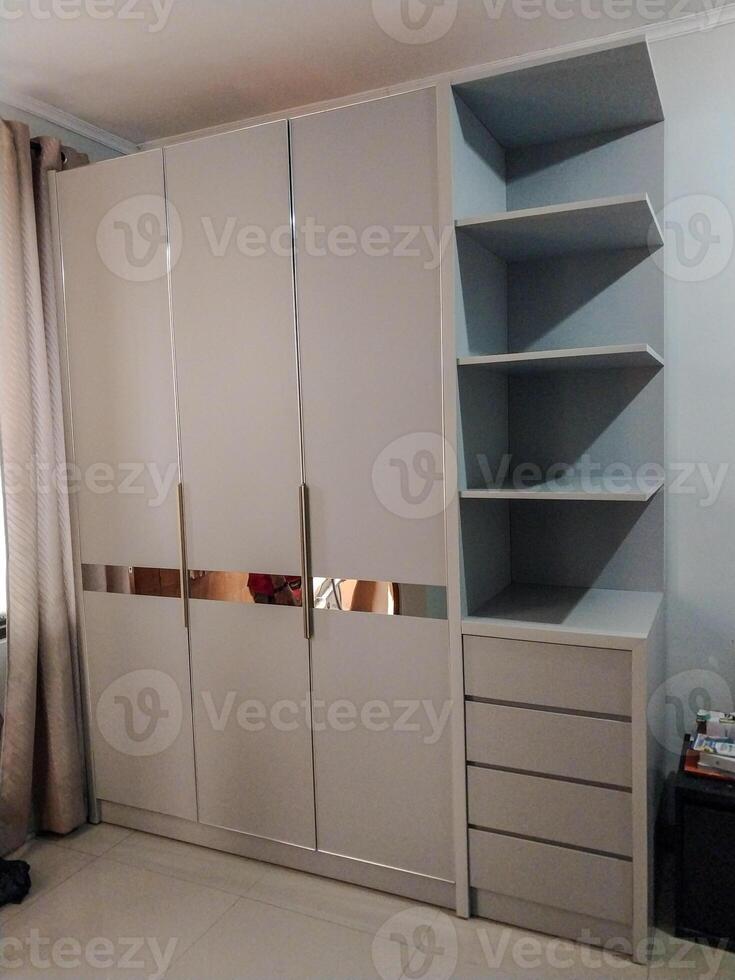 wardrobe with three doors with hanging shelves and drawers to the left of the cupboard. photo