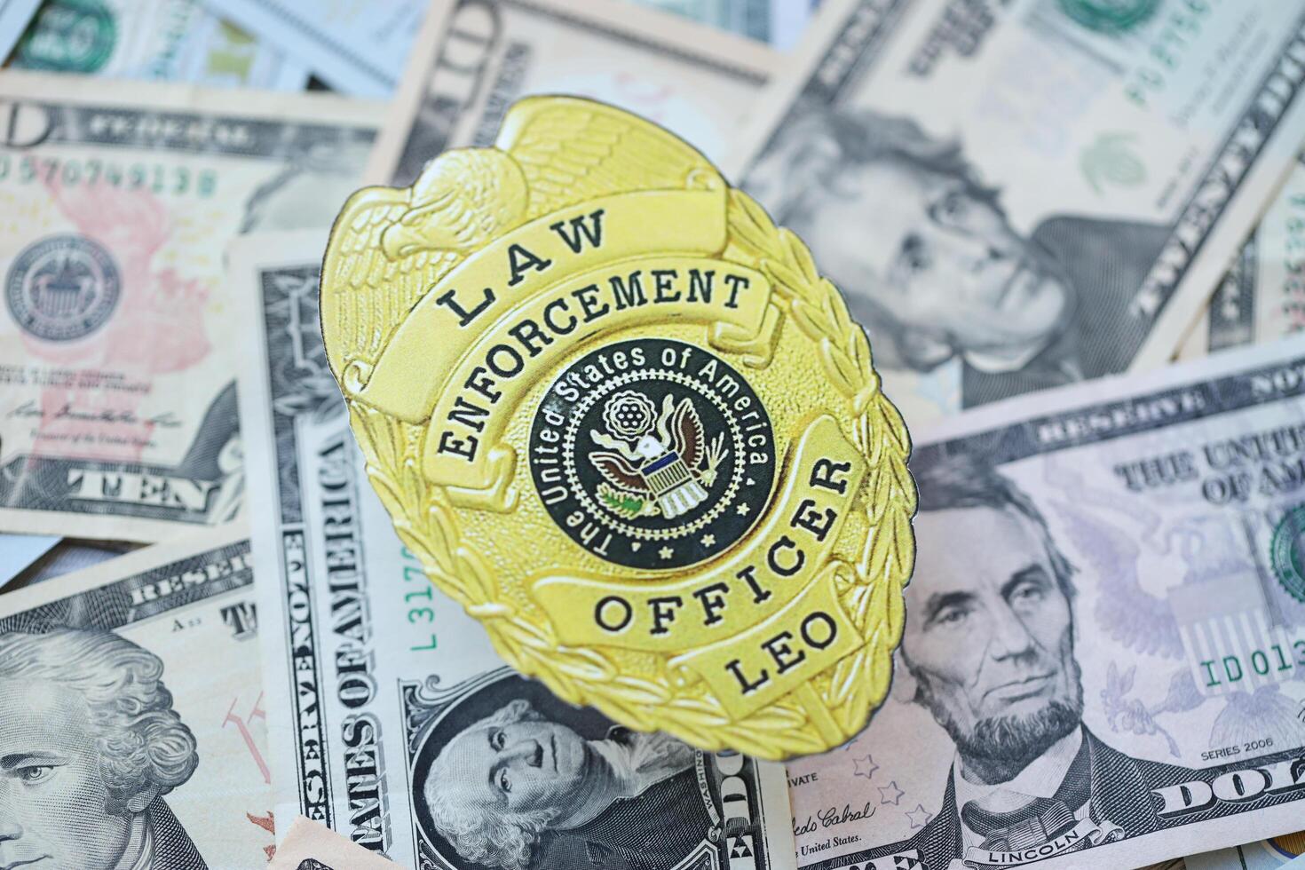 KYIV, UKRAINE - MARCH 9, 2024 US Law Enforcement Officer badge on many US dollar bills photo