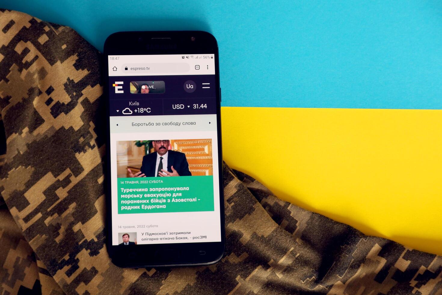KYIV, UKRAINE - 4 MAY, 2023 Espreso TV ukrainian news portal on smartphone screen with ukrainian flag and camouflage fabric photo