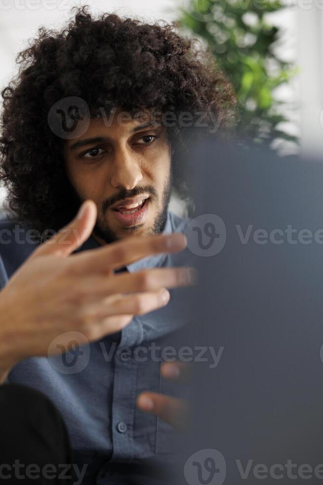 Marketing professional explaining project strategy plan to customer in online meeting. Arab entrepreneur attending corporate conference on laptop, talking with coworkers photo