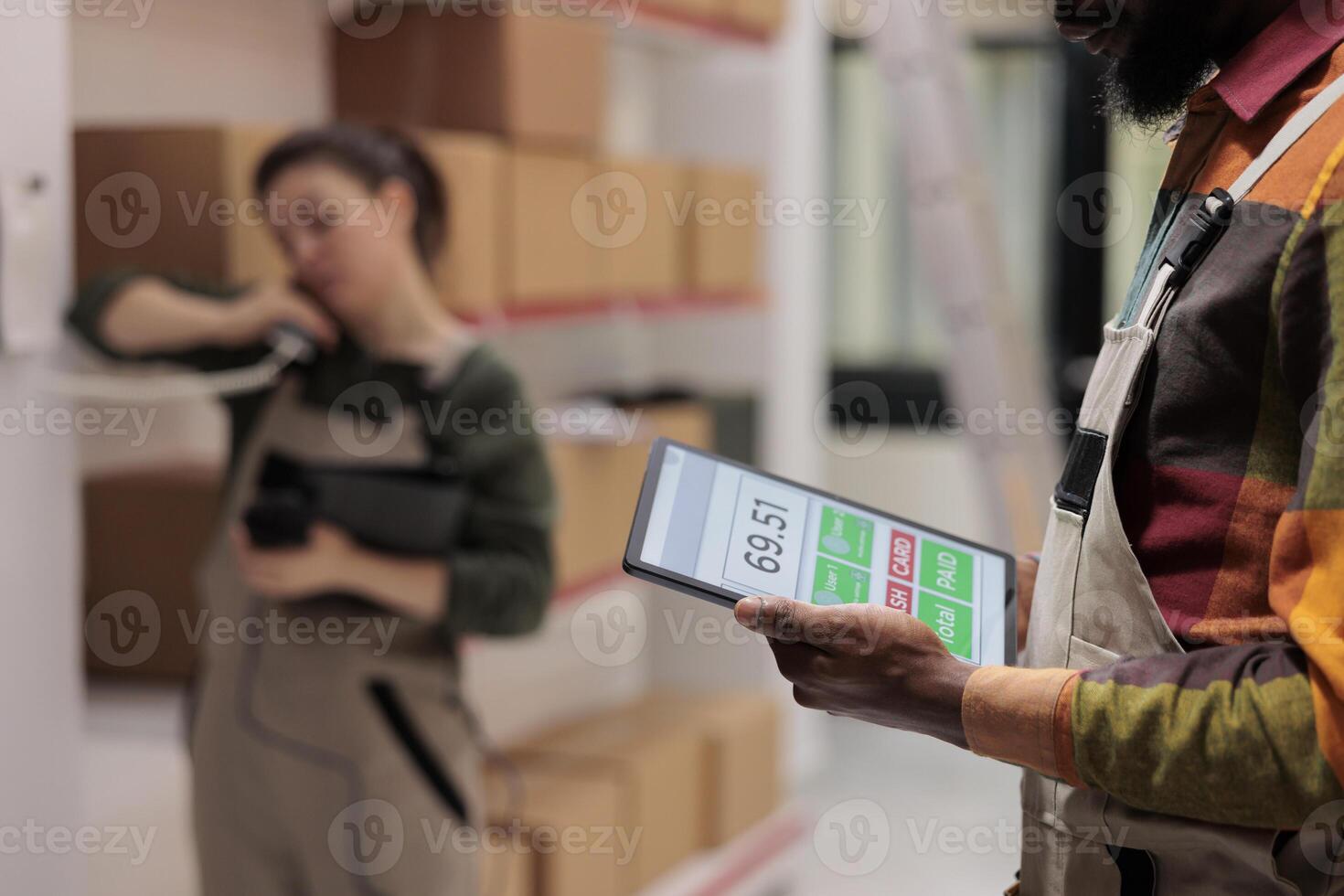 Warehouse supervisor holding tablet computer analyzing checklist, preparing clients order. Diverse employees working at packages delivery, scanning products in storage room. Close up concept photo