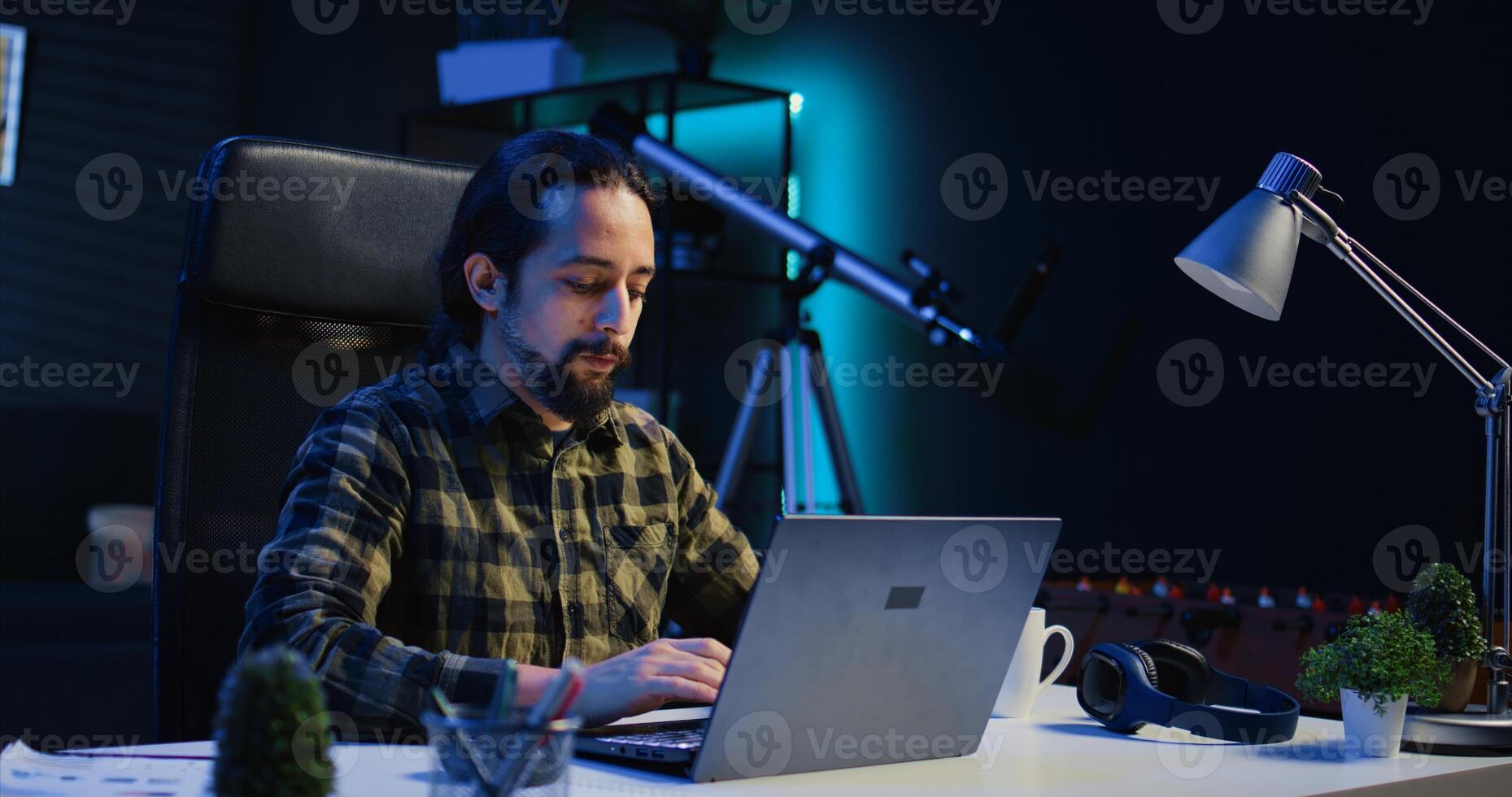 Focused freelancer working from home, typing on laptop, writing in document. Remote employee scrolling on digital device and sending emails to business associates, camera B photo