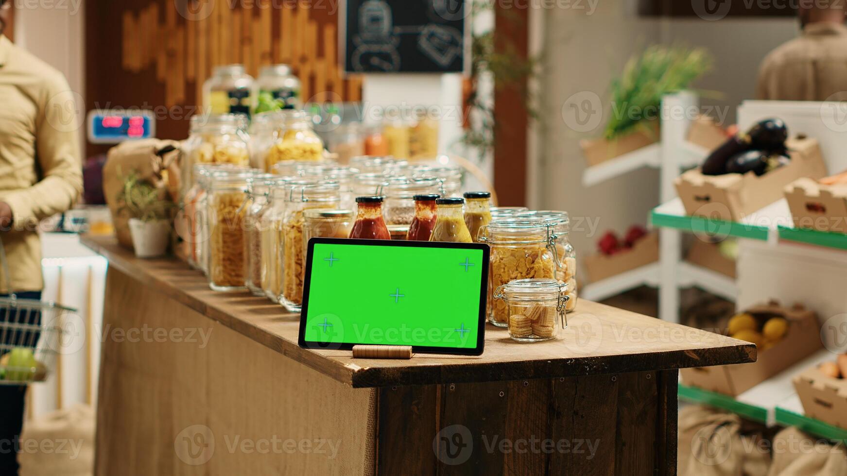 pantalla verde monitor mostrado en tableta a barrio tienda de comestibles almacenar, apoyo bajo carbón huella y eco simpático agricultura. artilugio con blanco copyspace diseño siguiente a abultar artículos en frascos. cámara 1. foto