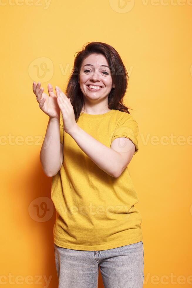 Cheerful female individual clapping hands to celebrate achievement while looking at camera. Caucasian woman with positive emotions applauding and doing appreciation claps for her friend. photo