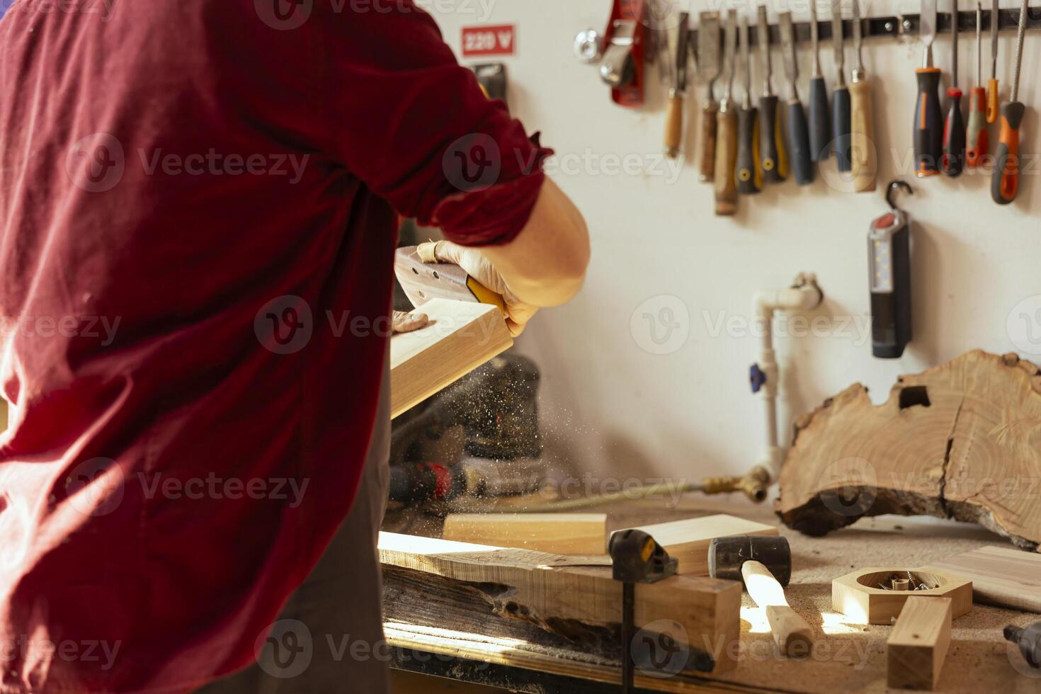 Manufacturer using sandpaper for smoothing wooden surface before polishing it, ensuring adequate finish. Woodworking professional using sanding sheets to fix damages suffered by lumber block photo