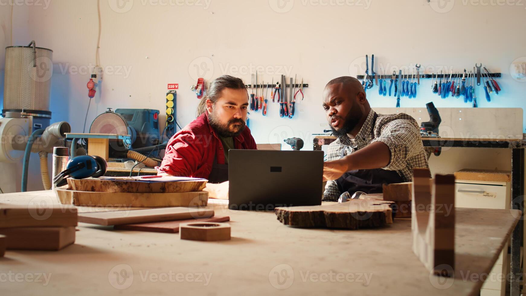 Woodworkers using CAD software on laptop to design wooden objects, pointing towards screen. Carpenters using program on notebook to help them do furniture assembling in joinery, camera B photo