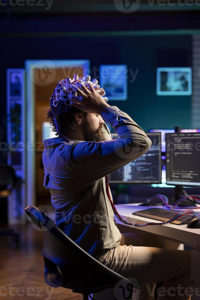 Software engineer puts EEG headset on, starting mind upload process, trying to gain bionic powers. IT admin using high tech neuroscientific gear to transfer consciousness into cyberspace photo