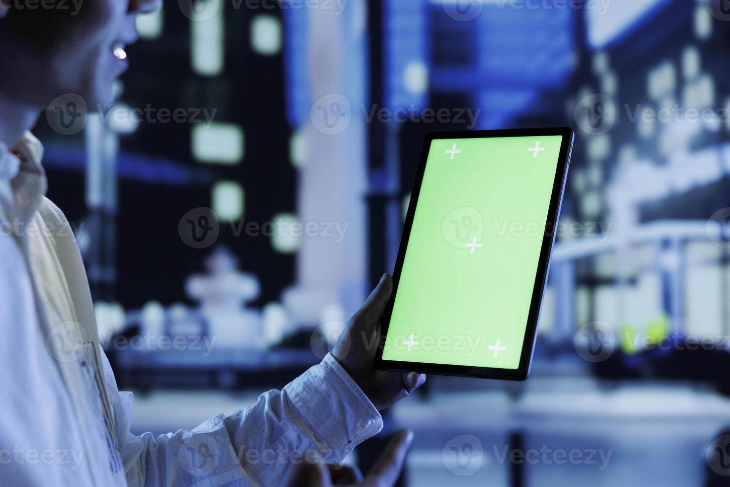Man having fun walking around city at night, scrolling on online shopping platform using green screen tablet, close up. Citizen using chroma key device while strolling on empty streets photo