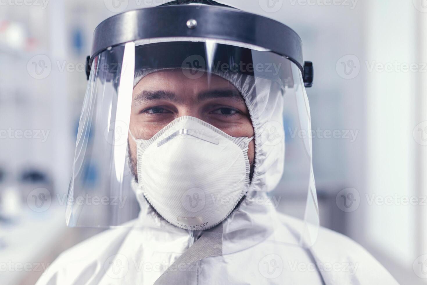 Portrait of biochemist in science laboratory wearing ppe equipment for covid19. Overworked researcher dressed in protective suit against invection with coronavirus during global epidemic. photo