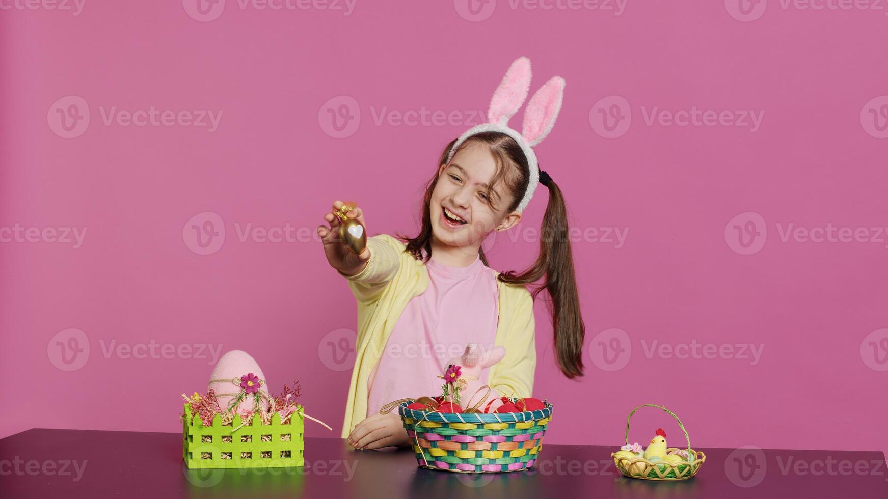 emocionado joven niña arreglando pintado huevos en un cesta a preparar para Pascua de Resurrección fiesta celebracion, creando festivo preparativos. juguetón contento niñito con conejito orejas, creativo actividad. cámara una. foto