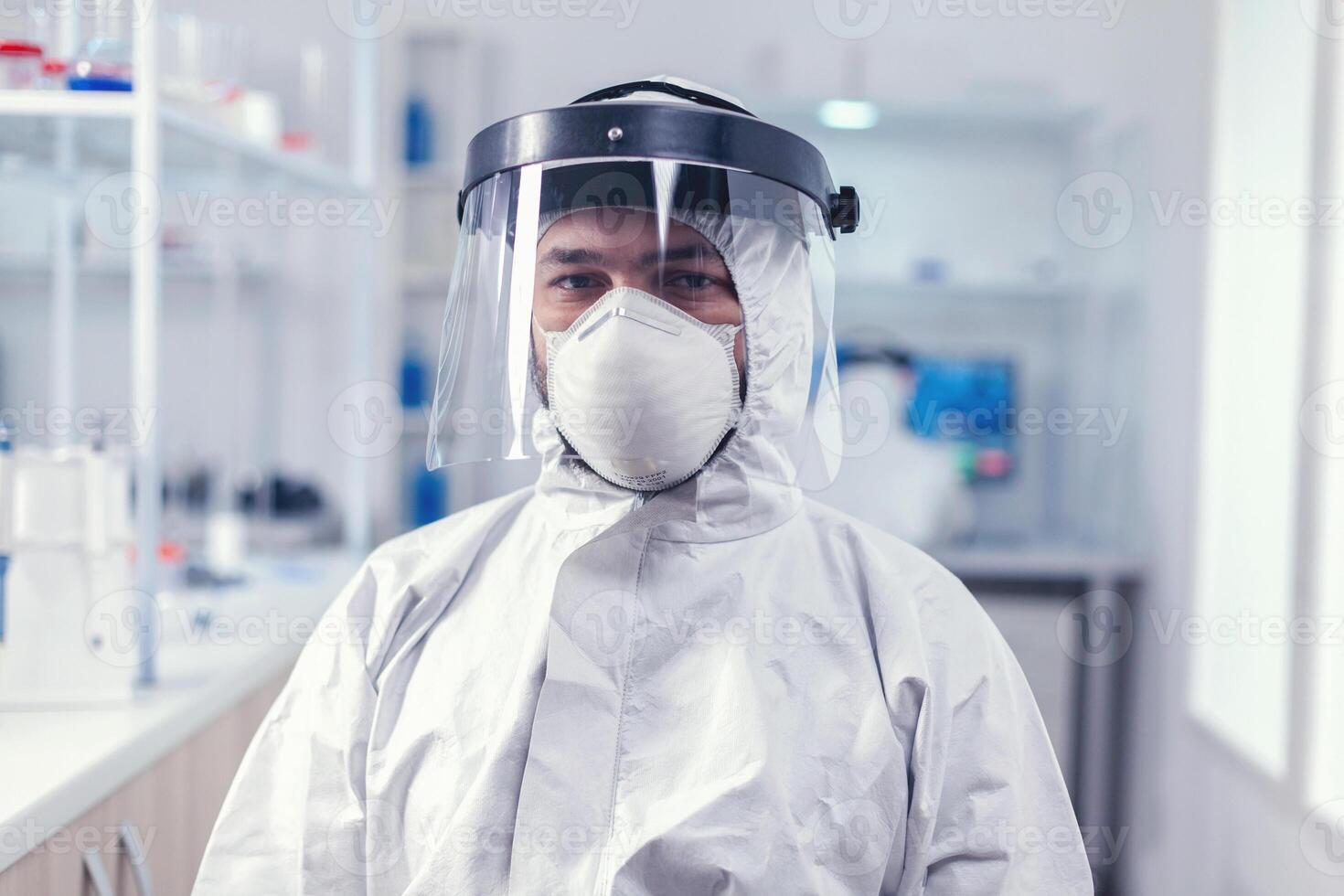 Biochemistry scientist wearing face mask and face shield as safety precaution for covid19 outbreak working in lab. Overworked researcher dressed in protective suit against invection with coronavirus during global epidemic. photo