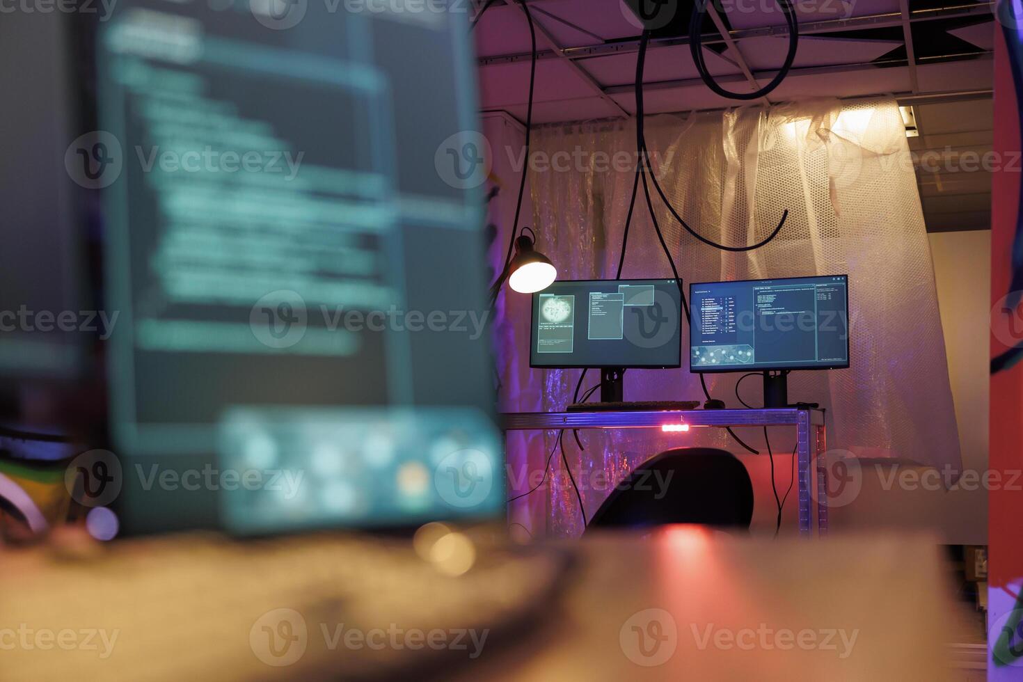 Computer screens with malware running code stealing sensitive information in hackers abandoned warehouse. Malicious software with internet virus on monitors in dark hideout with neon light photo