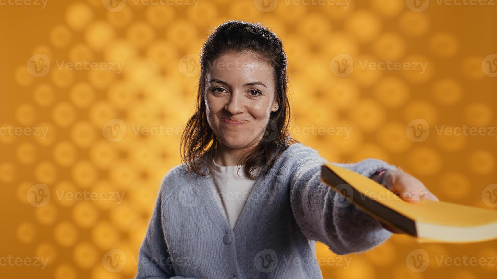 Portrait of upbeat content creator reviewing newly published books, presenting synopsis to audience. Media star sponsored by publisher to show new novel releases to subscribers, studio background photo