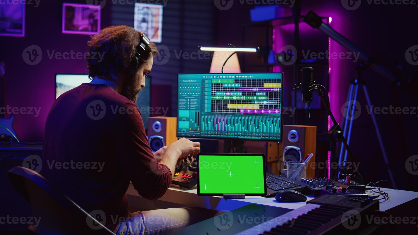 Musician mixing and mastering sounds at home studio with electronic console and soundboard, creating modern tunes. Sound engineer producing audio tracks with greenscreen on tablet. Camera B. photo