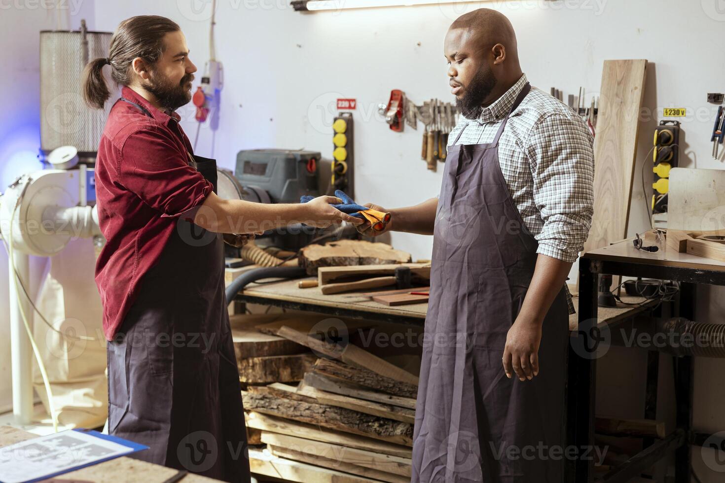 African american apprentice preparing to start production in furniture assembly shop, receiving equipment from master. BIPOC cabinetmaker first day at work, receiving protective gloves photo