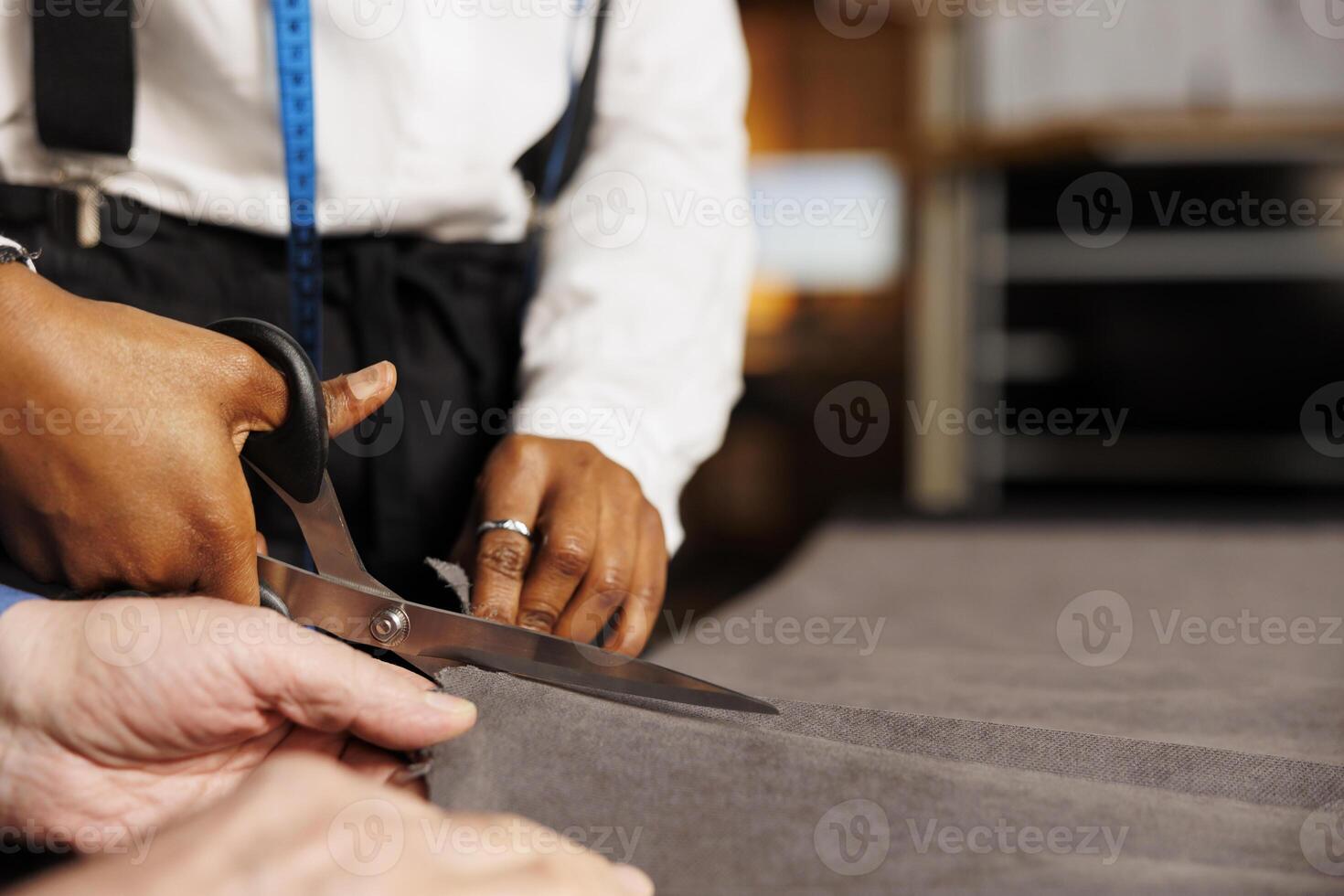 Extreme close up of seamstress using scissors to cut refined fabric material in professional atelier shop studio. Experienced dressmaker teaching tailor apprentice expert craftmanship photo