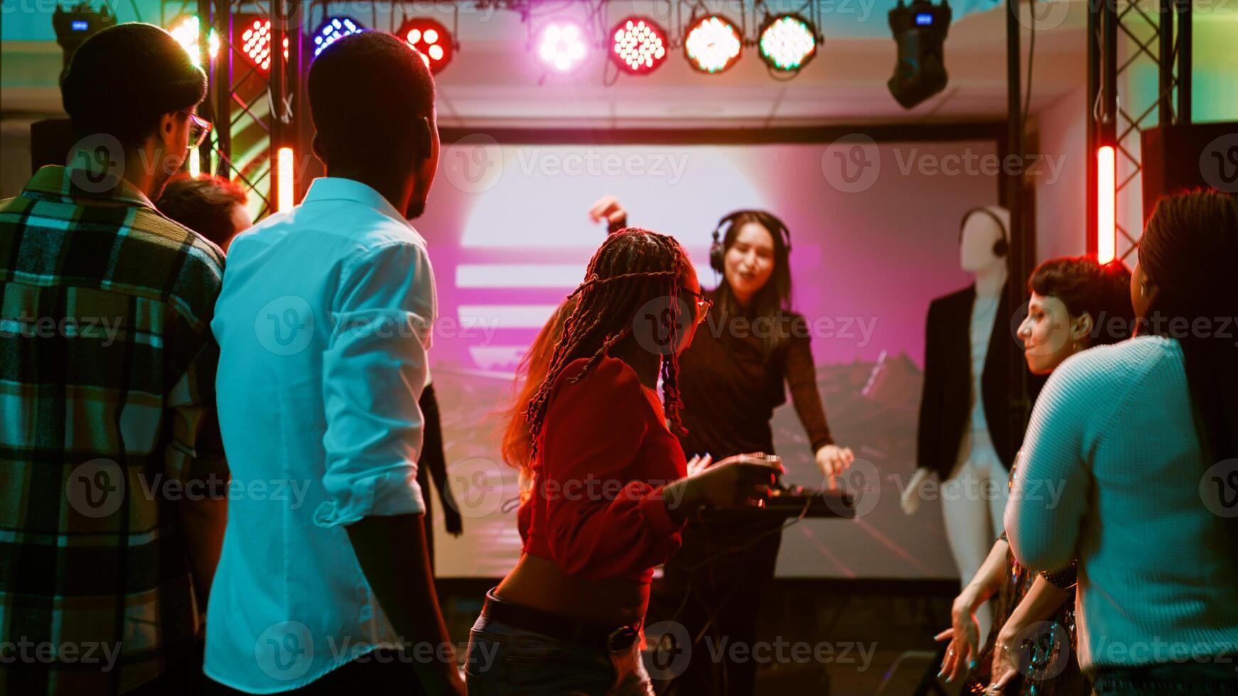 Men and women dancing at disco party, diverse people listening to electronic music at discotheque. Joyful adults enjoying night out celebration on dance floor, partying at club. Handheld shot. photo
