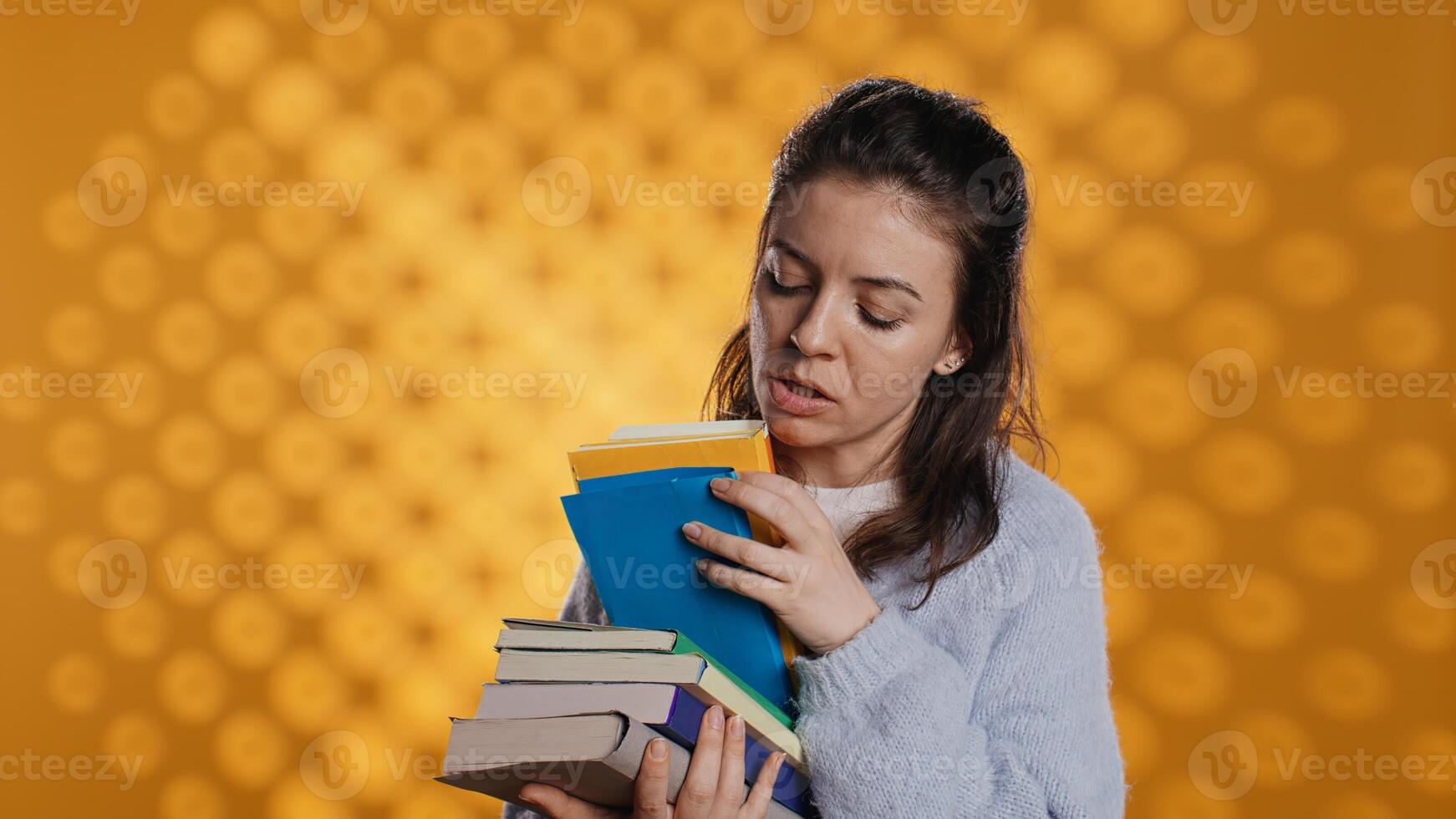 Excited woman browsing though pile of purchased books, picking what to read. Enthusiastic bookaholic person looking through stack of novels to spend leisure time with, studio background, camera B photo