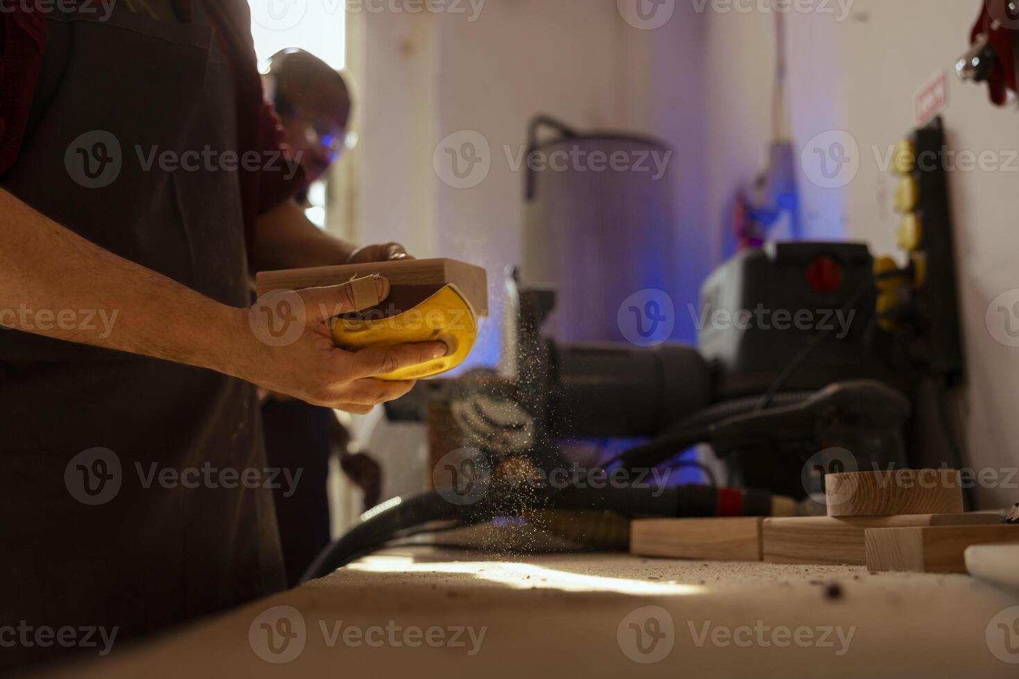 Man at workbench using manual sandpaper tool to sander timber block, assembling furniture in carpentry shop. Carpenter smoothing piece of wood, improving its appearance, close up shot photo