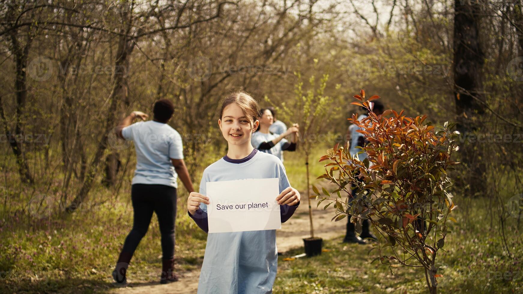 retrato de dulce niña con salvar nuestra planeta póster en contra contaminación y ilegal dumping, trabajar como voluntario a restaurar y preservar naturaleza en el bosque. pequeño niño muestra conciencia signo. cámara b. foto