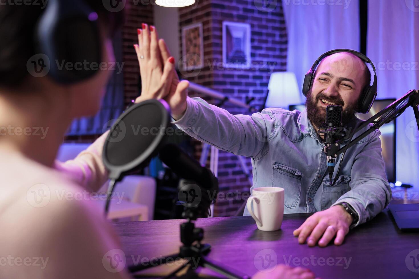 Show host interviewing woman during live stream, talking about fashion and style trends, agreeing with her opinions. Man high fiving social media content creator, recording podcast photo