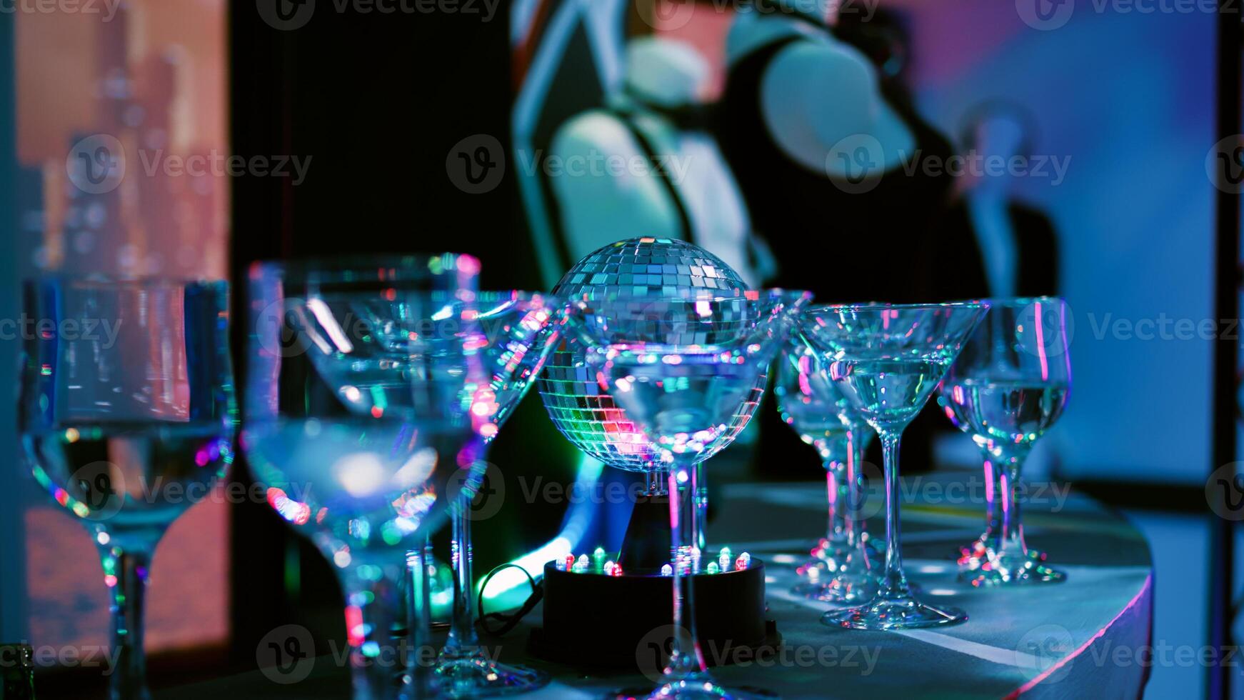 Empty club with alcohol in glasses, discotheque with stage lights and music at nightclub. Alcoholic drinks prepared for disco party and clubbing, live show. Close up. Handheld shot. photo