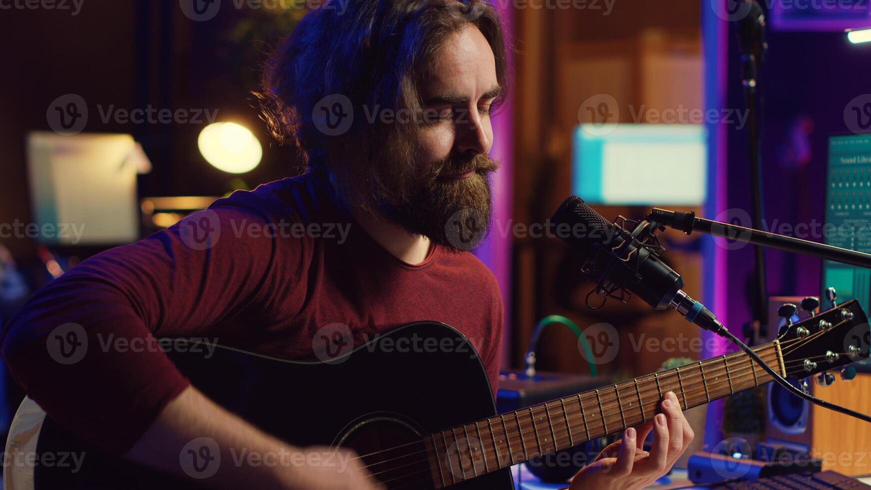 Artist with condenser microphone composing a song on guitar, working on mixing and mastering music. Producer recording tunes and adding sound effects in post production. Camera A. photo