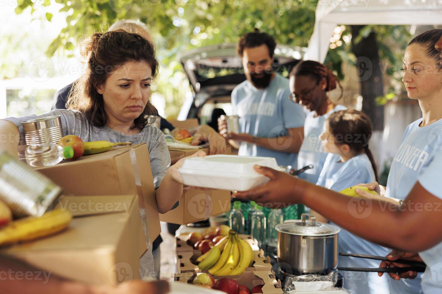 Multiracial group offers assistance by distributing food to the poor and needy. Volunteers of different ethnicities join together to aid homeless people by participating in humanitarian food drive. photo