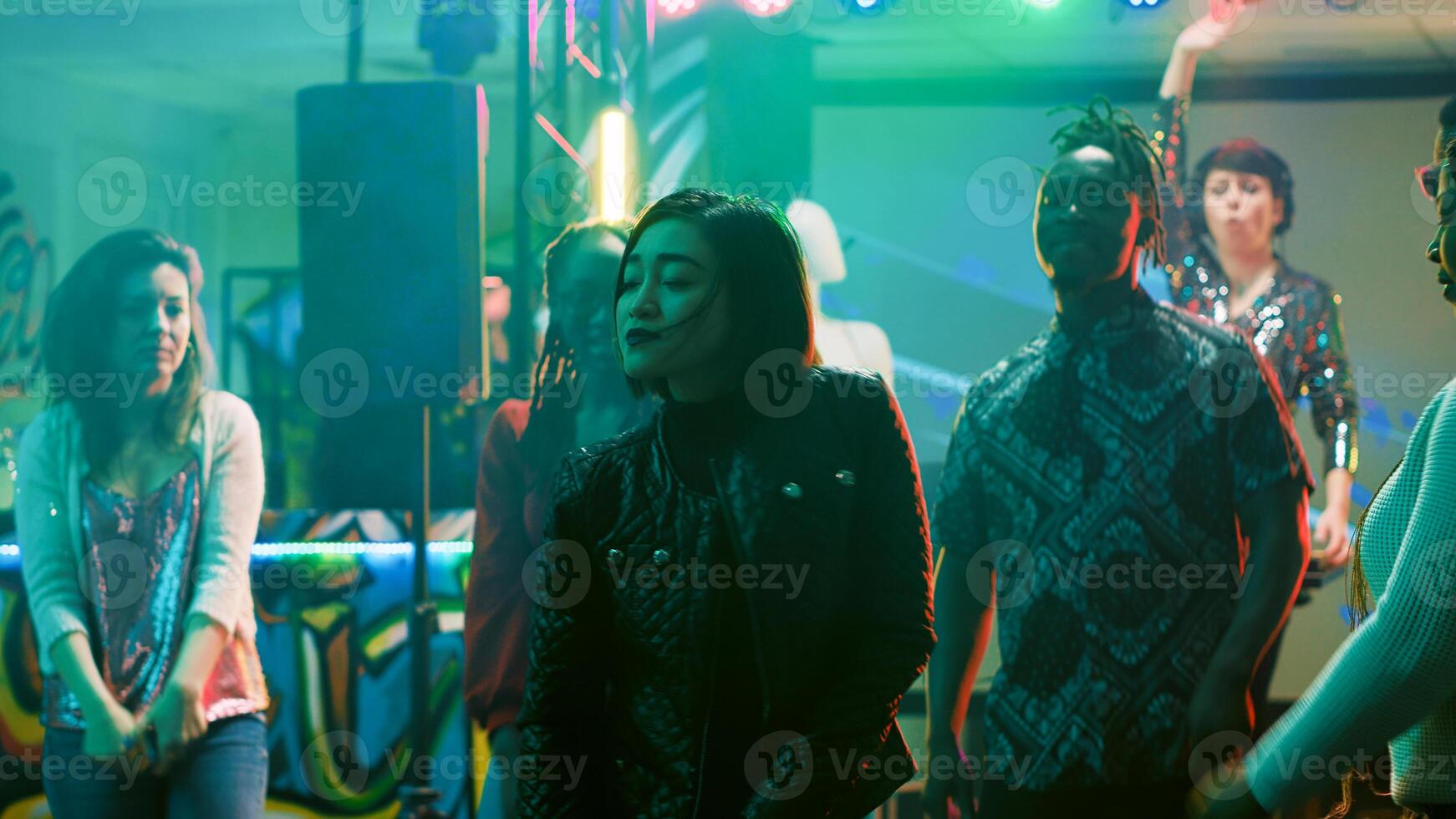 Female dancer partying at nightclub, feeling happy dancing on music. Group of people showing funky dance moves on dance floor, partying together with discolights. Tripod shot. photo